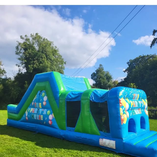 Blue and green inflatable obstacle course with a small slide on a lawn.